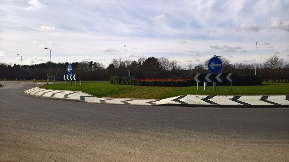 Motorway Infrastructure & Design image of empty roundabout with flowers to centre and white and black chevrons bordering